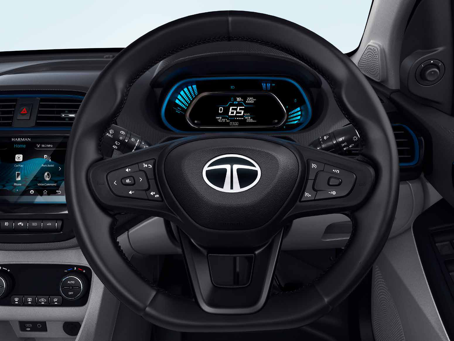 Tata Tigor EV — Fully digital instrument cluster displaying state of charge, range and drive mode, behind a flat-bottom steering wheel with audio, phone and cruise controls