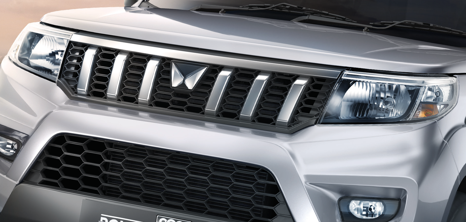 Mahindra Bolero Neo Plus — Signature grille with chrome inserts, flanked by twin-pod headlamps