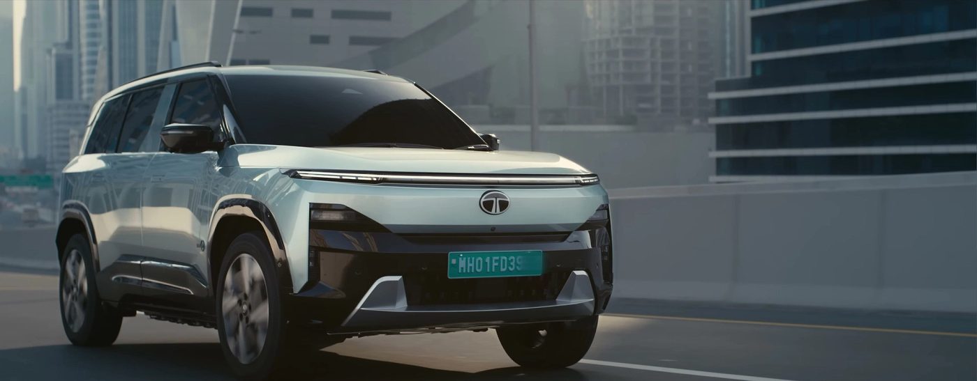 Tata Sierra.ev front three-quarter view on a Dubai flyover, showing the full-width LED light bar and Tata badge