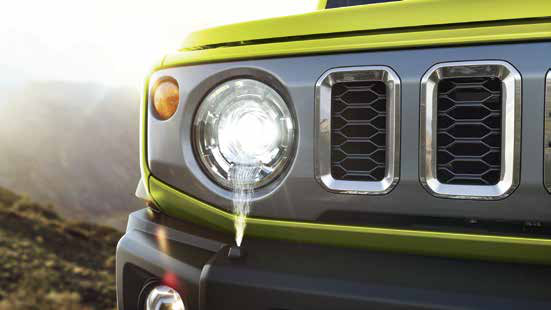 Maruti Suzuki Jimny — Round LED projector headlamp sits beside the vertical-slot honeycomb grille.