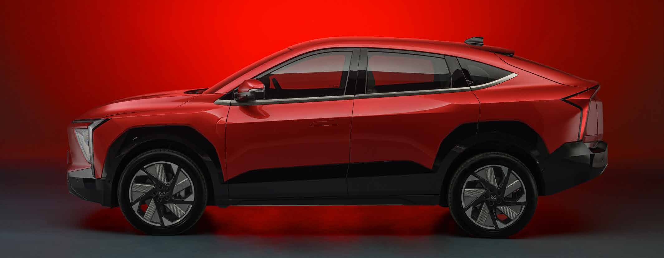 Mahindra XEV 9e — Coupe roofline side profile with black cladding and aerodynamic alloy wheels