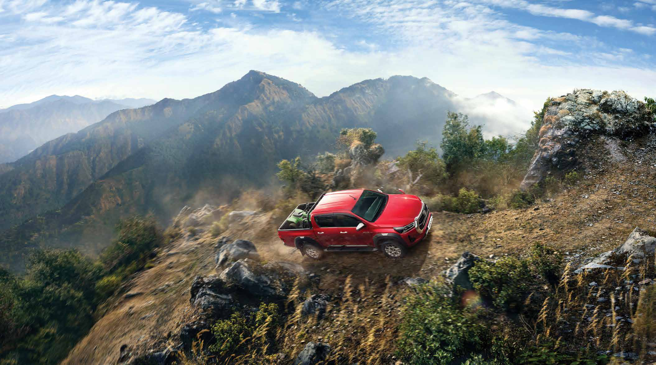 Toyota Hilux (2022-2025) — Four-wheel-drive capability climbing a rugged mountain trail.